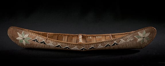 Photographie d'un petit canoë d'écorce mi'kmaq décoré de motifs en piquants de porc-épic et destiné à la vente touristique.