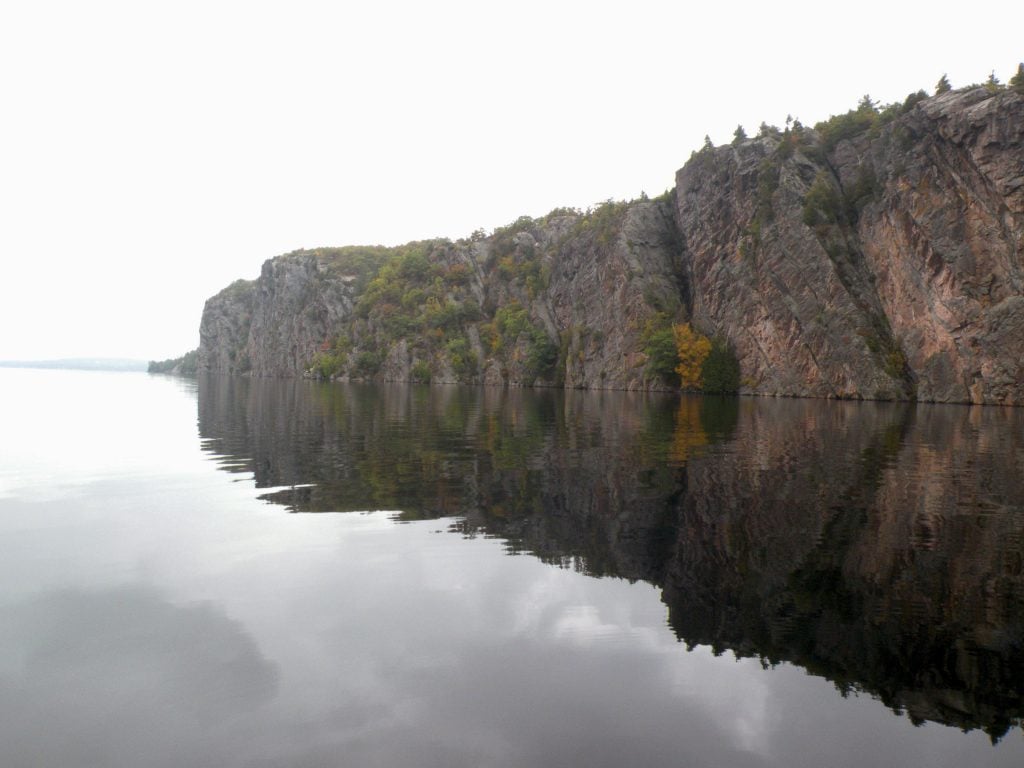 Photographie de l'immense falaise du site de Bon Écho situé au lac Mazinaw en Ontario. S'élèvant jusqu'à 100 mètres au-dessus du lac et s'étendant sur 1,5 kilomètre, ce lieu regroupe plus de 260 pictogrammes.