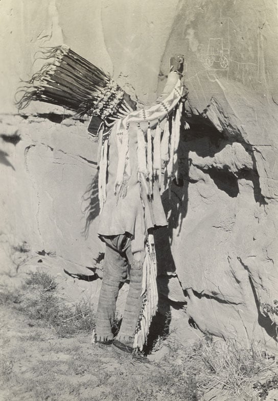 Photographie de Bird Rattle, un aîné Niitsítapi (Pieds-Noirs), exécutant l'une de ses dernières gravures à Áísínai'pi en 1924. Photo par Roland H. Willcom, 1924. Alberta, Canada