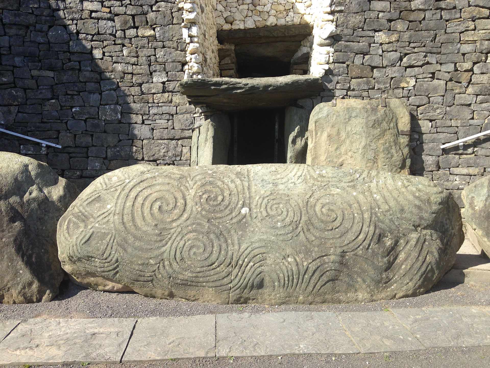 Photographie d'un bloc orné de gravures en spirale et autres représentations géométriques. Newgrange, Brú na Bóinne, Irlande