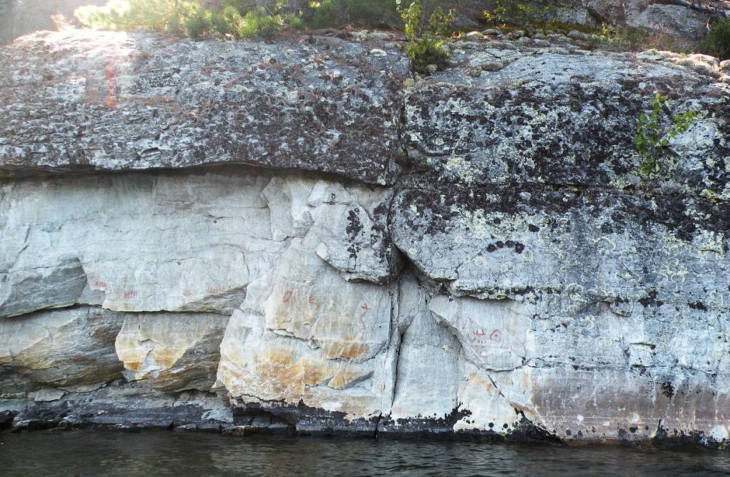 Photographie du site de Diamond Lake en Ontario, au Canada. Sur un afleurement rocheux sont représentés un Serpent cornu, des canoës et une empreinte de patte d’oiseau.