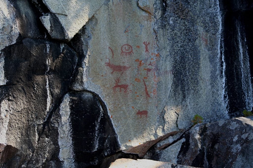 Missinaibi Lake cliff on which several representations, including caribous, a bear and a face, are painted.