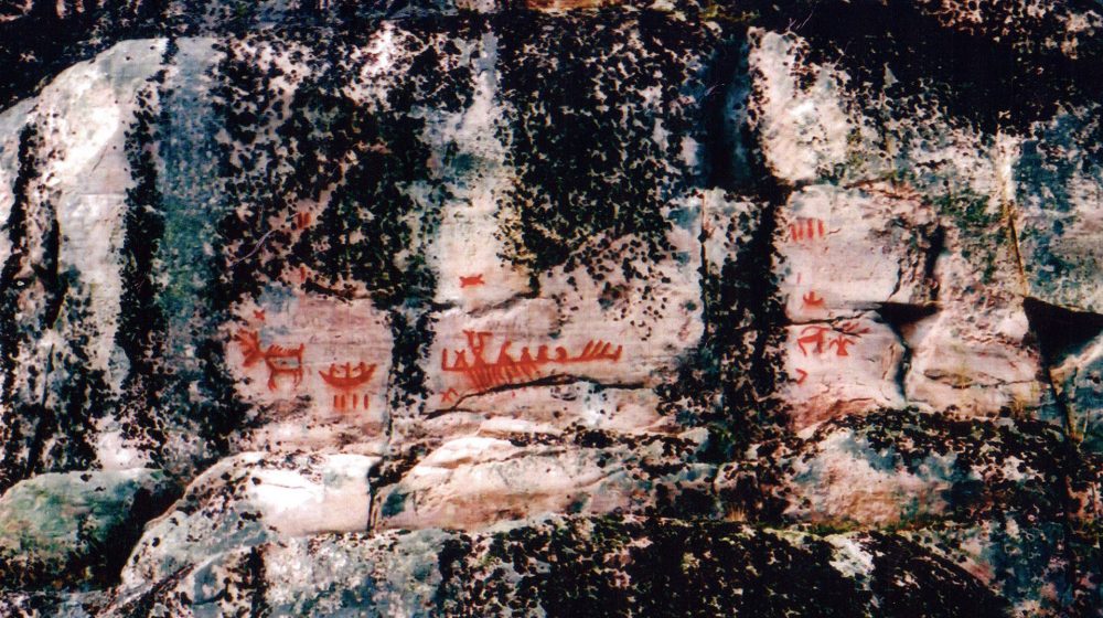 Paimusk Creek site in Manitoba. Several rock paintings are found at this place, including a caribou or a moose, a canoe with three occupants, a Thunderbird, as well as more or less complex geometric motifs.