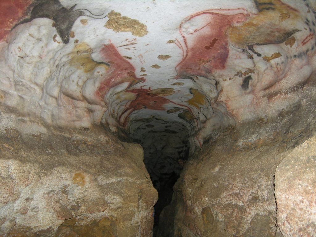 Photographie de la grotte ornée de Lascaux en France. On voit ici la voûte de l’entrée du Diverticule axial, un long conduit qui a été peint de motifs figuratifs et géométriques polychromes; les zoomorphes illustrés forment un bestiaire composé d’aurochs et de chevaux sauvages.